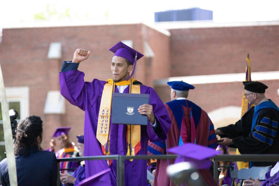 一名毕业生在拿到大学学位后挥舞着拳头